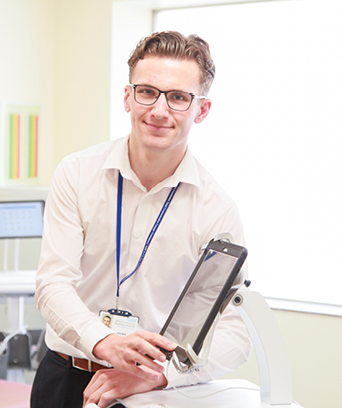 Male smiling at camera pointing to iPad screen