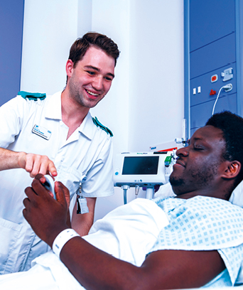 Male adult nurse tending to patient in bed