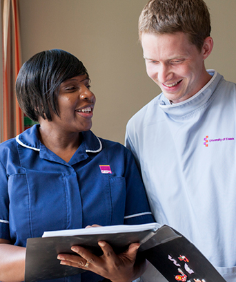 Two NHS staff members looking at document book