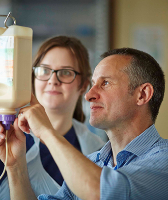 Two NHS staff members looking at hospital drip pouch