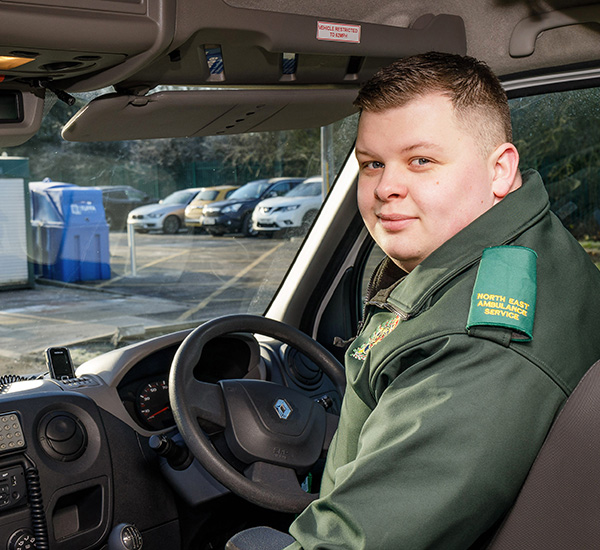 Male paramedic sitting in driver's seat of ambulance