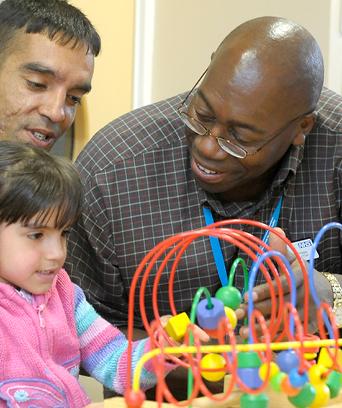 Two males sitting with female child playing with toy