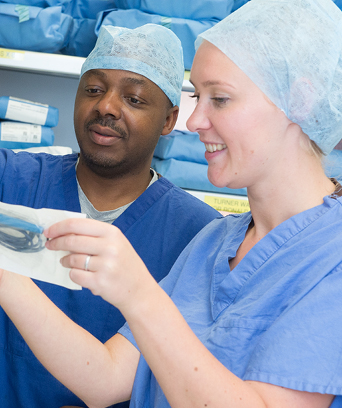 Two NHS staff members in scrubs looking at equipment