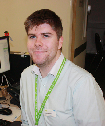 Male sitting at desk smiling at camera