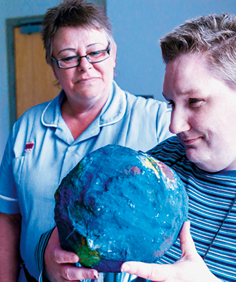 Female nurse with female patient looking at craftwork