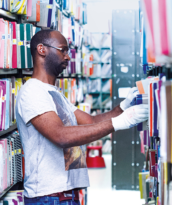 Male in gloves tidying documents on library shelves