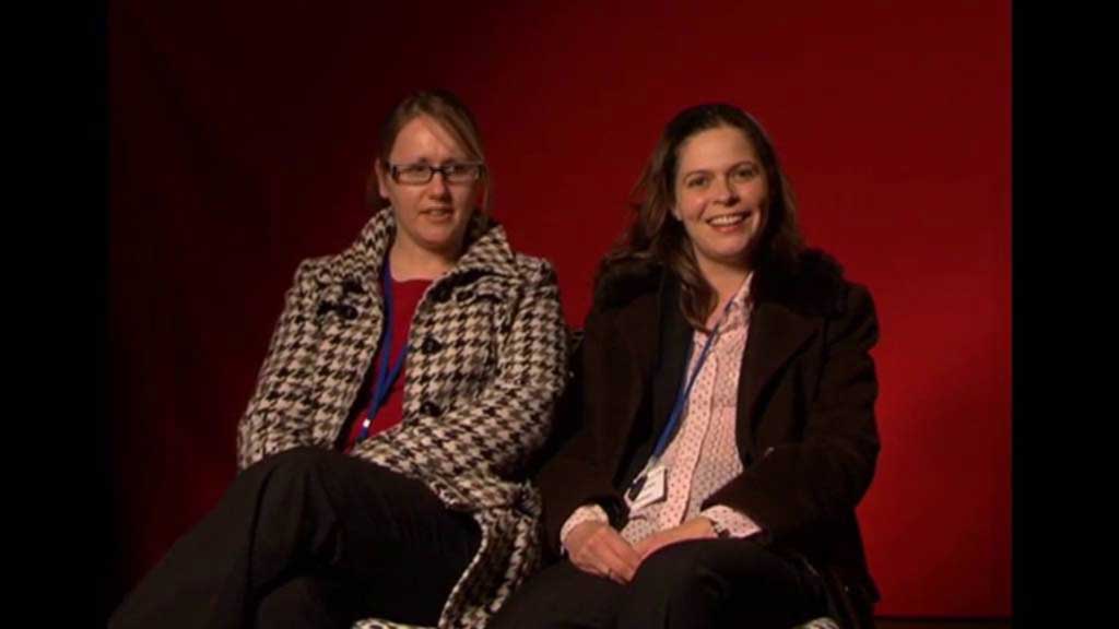 Two females, sitting and looking at camera