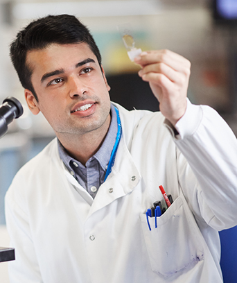 Male scientist in lab coat looking at sample