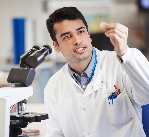 Male scientist in lab coat looking at sample