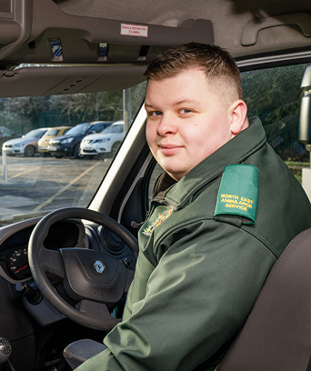 Male paramedic sitting in driver's seat of ambulance