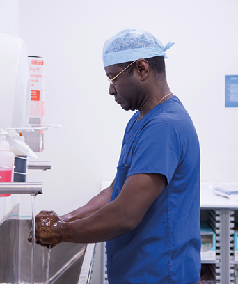 Male surgeon in scrubs washing hands