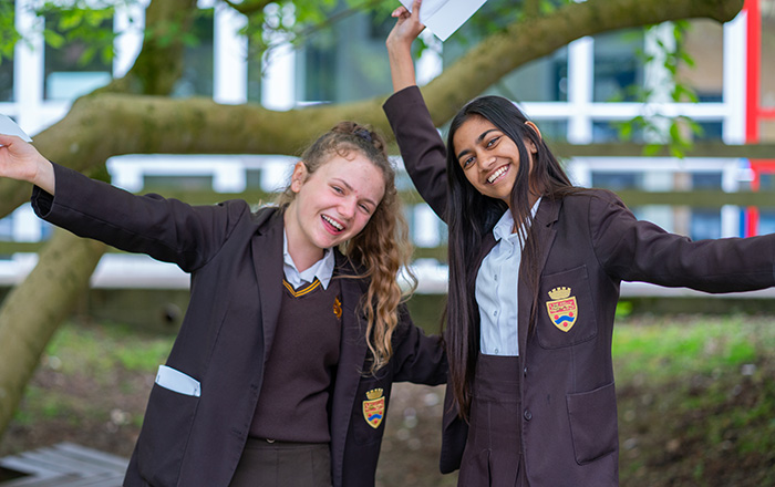 Two female students in uniform celebrating