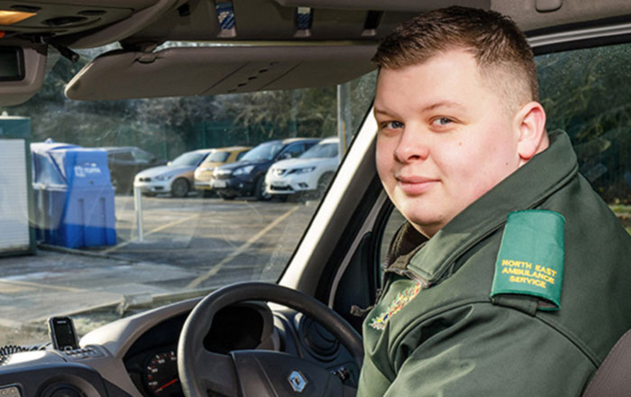 Male paramedic sitting in driver's seat of ambulance